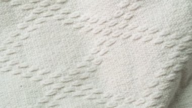 Beyaz tekstil dokusu, yakın çekim. Kamera beyaz kumaş boyunca yavaşça kayıyor. Tekstil deseni, soyut arkaplan. Seçici yumuşak odaklanma. Bulanık arkaplan.