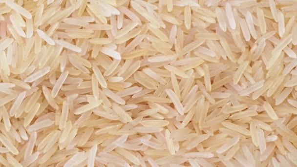Ungekochter weißer Reis, Nahaufnahme. Dolly Schuss Haufen von weißem Reis. Textur von Reis, abstrakter Hintergrund. Selektiver weicher Fokus. Unklarer Hintergrund. — Stockvideo