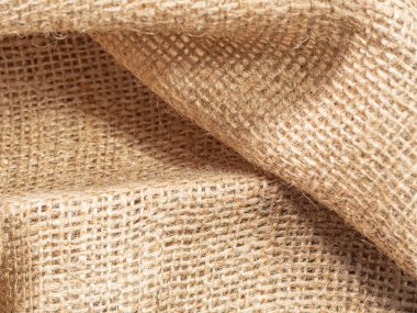 Kahverengi buruşuk balenin yakın görüntüsü. Kahverengi çuval bezi tekstilinin soyut arkaplanı. Kahverengi çuval bezi dokusu. Seçici yumuşak odaklanma. Bulanık arkaplan.