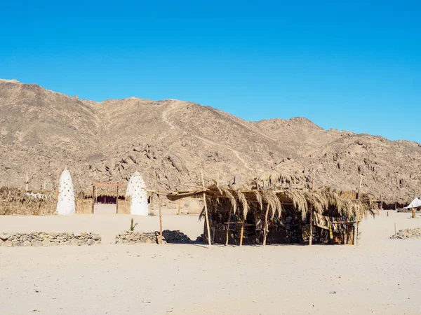 Egyptian mountain, long view. Reed shed with exotic fabric before mountain. Bedouin village. Blue sky is clear. Egyptian desert in February. Selective soft focus. Blurred background.