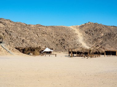 Mısır çölündeki Bedevi köyü, uzun manzara. Gri dağın üzerinde açık mavi gökyüzü. Reed dağ için önce barakalar. Seçici yumuşak odaklanma. Bulanık arkaplan.