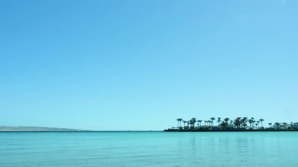 Paisaje marino de costa egipcia, tiro ancho extremo. Cielo azul despejado. Palmeras verdes en el horizonte. Fotografiado en Hurghada, Mar Rojo. Enfoque suave selectivo. Fondo borroso . — Vídeos de Stock