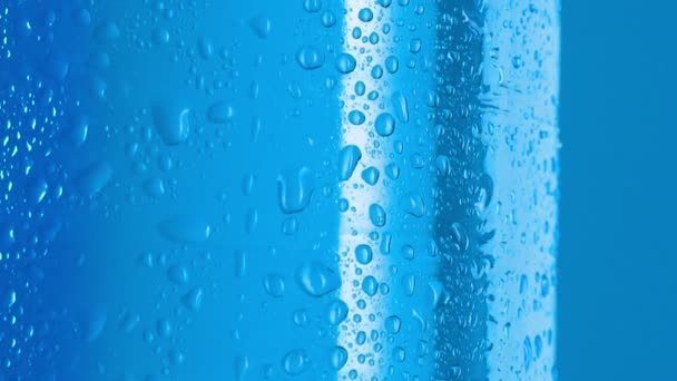 Water druppels op plastic fles tafelwater, macro shot. Dolly shot fles bedekt met condensaat. Abstracte blauwe achtergrond. Selectieve zachte focus. Wazige achtergrond. — Stockvideo