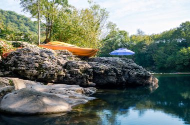 Turuncu tekne ve mavi şemsiye ormandaki nehir kenarında.