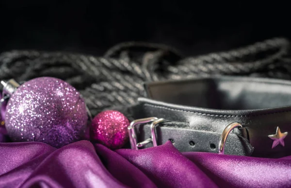 BDsm hala siyah deri yakalı Shibari halatı ve pembe kumaş üzerinde leylak rengi Noel topu.