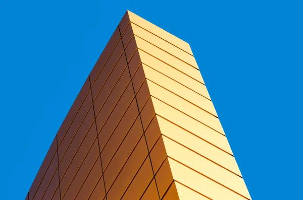 Fragmento de la pared de un moderno edificio amarillo sobre un fondo azul — Foto de Stock