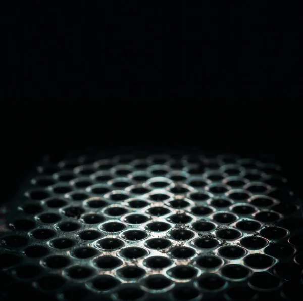 Superfície de mesa perfurada de metal em um close escuro — Fotografia de Stock