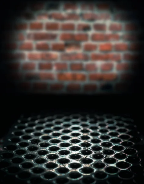 Superfície de mesa perfurada de metal em um porão escuro contra uma parede de tijolo — Fotografia de Stock