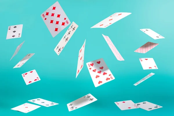 Turkuaz arka planda pek çok uçan iskambil kartı