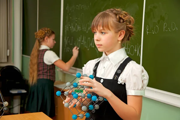 黒板の近くの女子高生は分子の模型を手に持っている — ストック写真