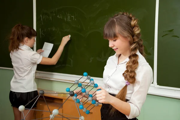 黒板の近くの女子高生は分子の模型を手に持っている — ストック写真