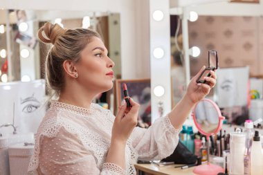 Muhteşem sarışın makyaj aynasında dudak boyuyor.