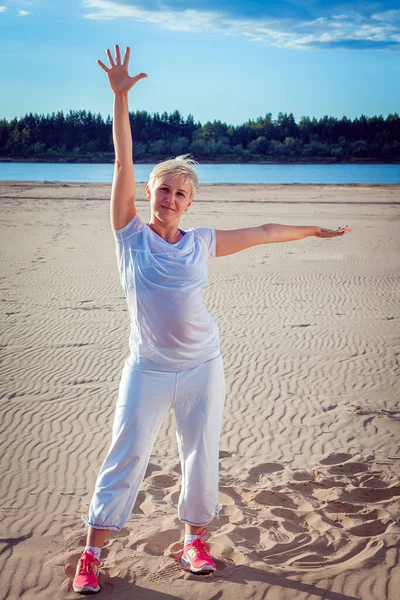 Woman Short Blond Hair White Tracksuit Sandy Beach Does Exercises — Stock Photo, Image