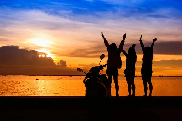 Grup de fete tinere fericite care stau pe plajă la apusul soarelui — Fotografie, imagine de stoc