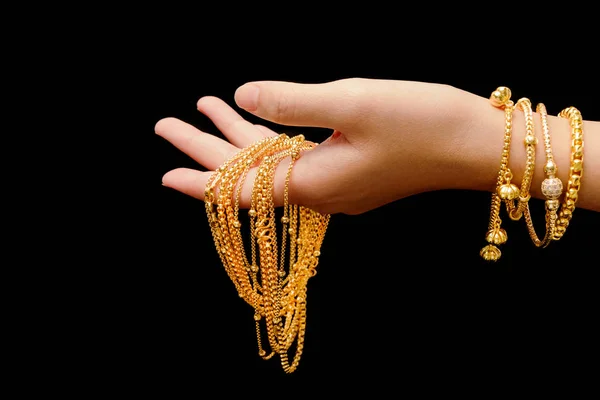 Woman's hand with many different gold jewelry on black backgroun — Stock Photo, Image