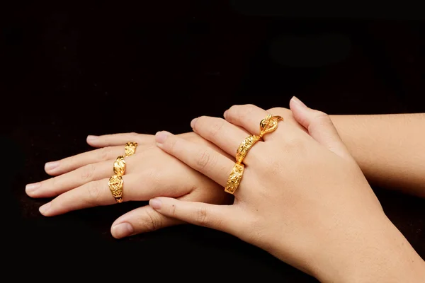 woman's hand with many different gold rings on black background
