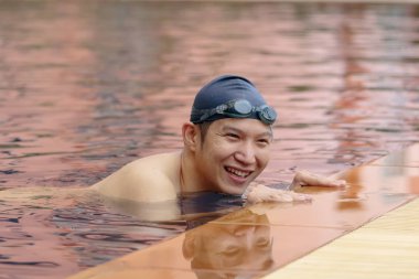 Asya yakışıklı Havuzda yüzmek kap ve gözlük takıyor