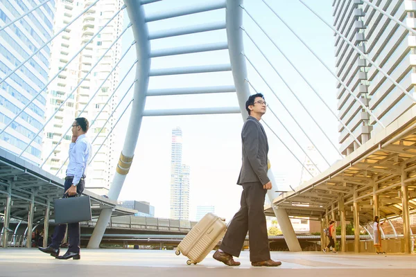 Uomo d'affari tirando valigia a piedi nella città moderna, concetto astratto di business . — Foto Stock