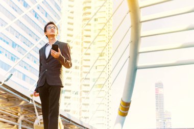 Şehir arka planda Smartphone kullanarak rahat iş adamı