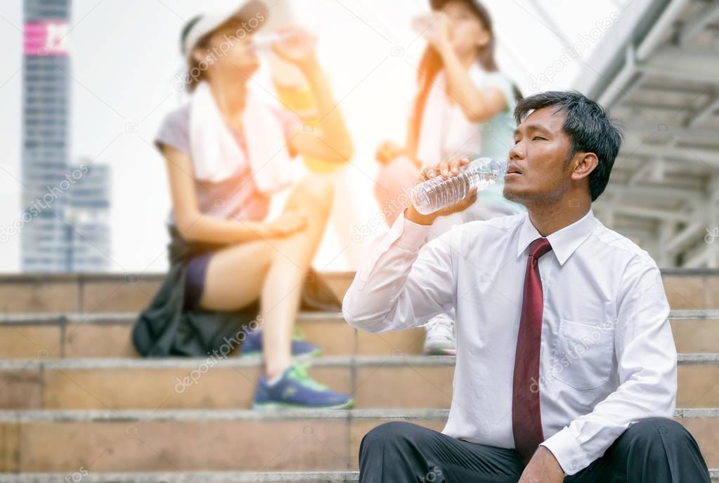 Businessman drinking water from a bottle after walking on street