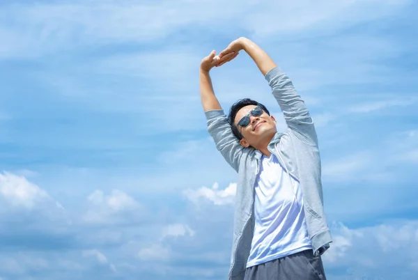 Uomo atletico che allunga le braccia nel cielo blu — Foto Stock