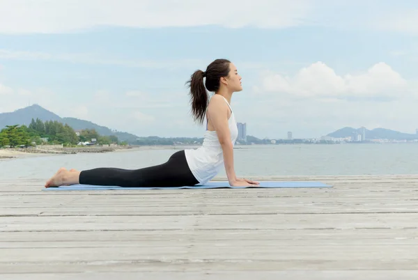 Mujer asiática joven practicando yoga en la orilla del mar —  Fotos de Stock