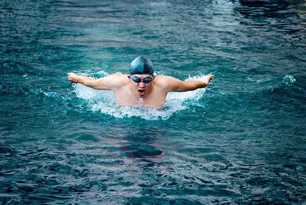 Swimmer in cap breathing performing the butterfly stroke — Stock Photo, Image