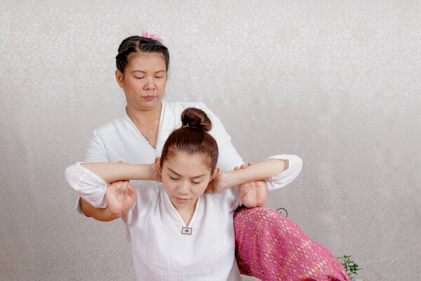 Asian woman getting traditional thai stretching massage by thera