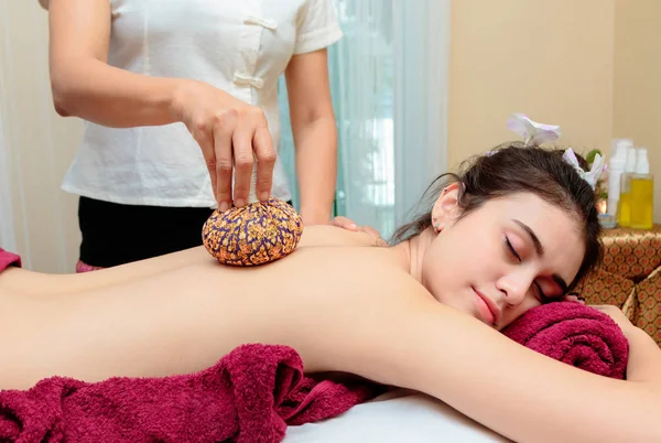 Asiatische Frau bekommen thailändische Kräuterkompresse Massage in spa. — Stockfoto