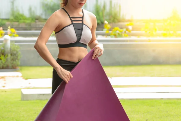 Attrayant jeune femme pliant tapis de yoga ou tapis de fitness après wor — Photo
