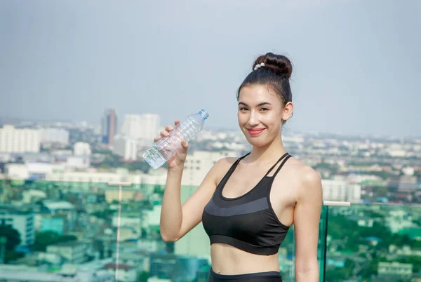 Счастливая женщина в спортивной одежде питьевая вода после тренировки в cit — стоковое фото
