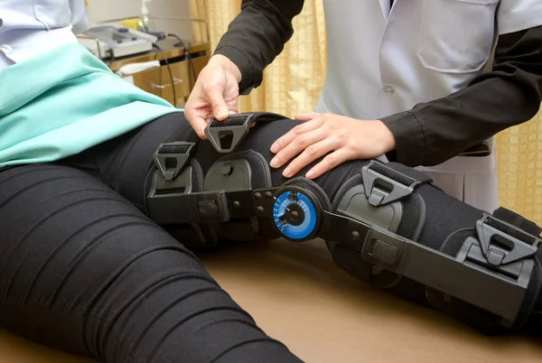 Fisioterapeuta ajustar los frenos de rodilla en la pierna del paciente, Rehabilitación para lesión de rodilla — Foto de Stock