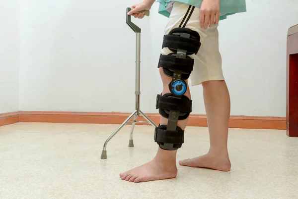 Woman walking on crutches, wearing knee support in rehab center — Stock Photo, Image