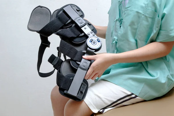 Injured woman with leg splint sitting on bed in rehab center — Stock Photo, Image