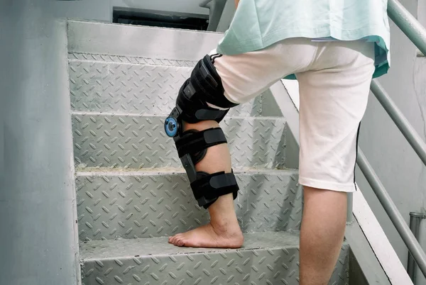 Patient with knee brace in moving upstairs — Stock Photo, Image