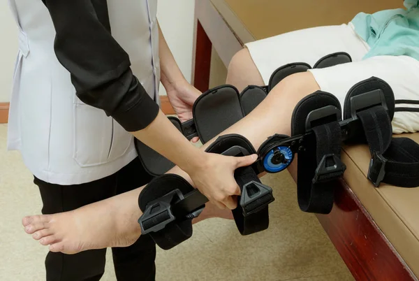Montage van een knie brace aan patiënt been therapeut — Stockfoto