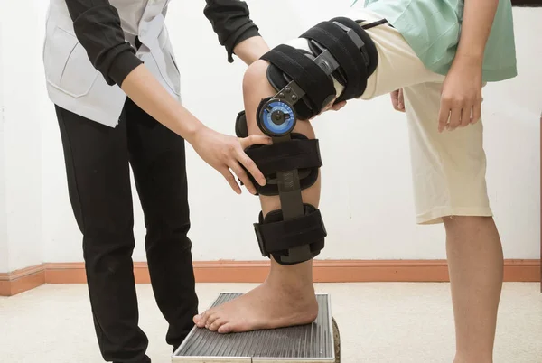 Terapeuta che adatta un tutore al ginocchio alla gamba del paziente — Foto Stock
