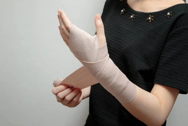 Mulher aplicando bandagem no pulso sozinha — Fotografia de Stock