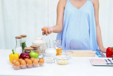 Pregnant woman preparing meal at table in the kitchen,healthy nu clipart