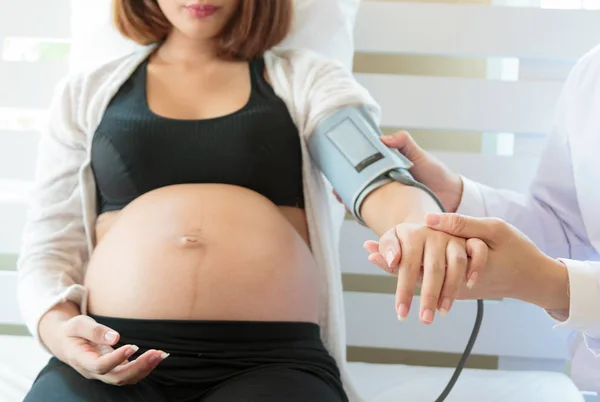 Врач проверяет кровяное давление беременной женщины в больнице — стоковое фото