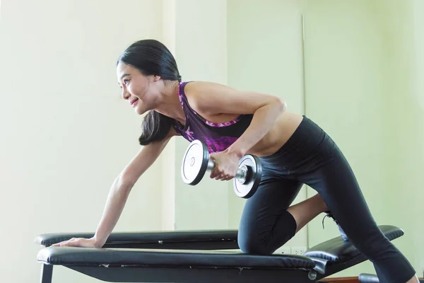 Young athletic woman doing an exercise with a dumbbell on a spor — Stock Photo, Image