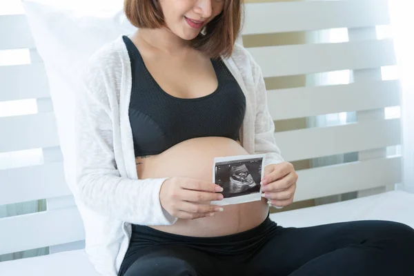 Happy pregnant woman is showing the ultrasound image. — Stock Photo, Image