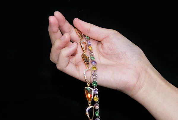 Woman hand hold jewelry bracelet on black background