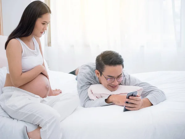 Donna incinta e suo marito utilizzano smartphone a casa insiemethe — Foto Stock