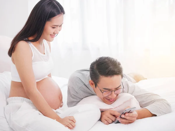 Těhotná žena a její manžel pomocí smartphone na domácí togethe — Stock fotografie