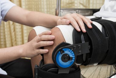 Kadın fizyoterapi hastanın bacak üzerinde yürüyen küme ayracı ayarlama