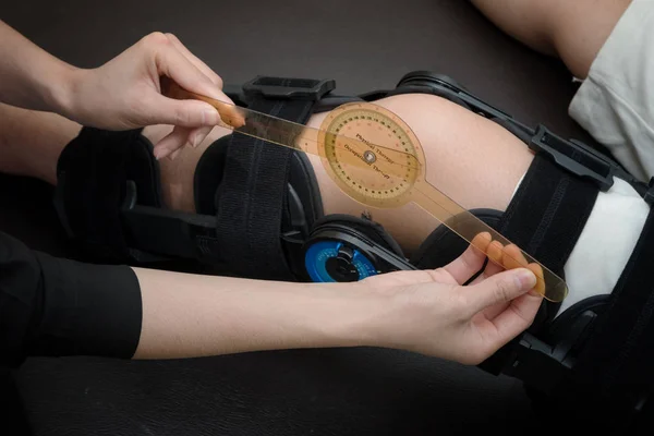 Physiotherapist measuring range of motion on patients' knee with — Stock Photo, Image