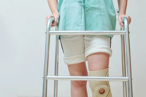 Woman in knee support walking on walker