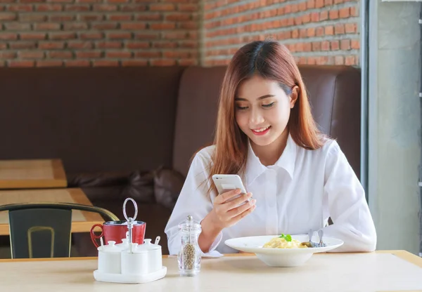 Glückliche Frau beim Mittagessen im Restaurant und beim Telefonieren mit dem Smartphone — Stockfoto
