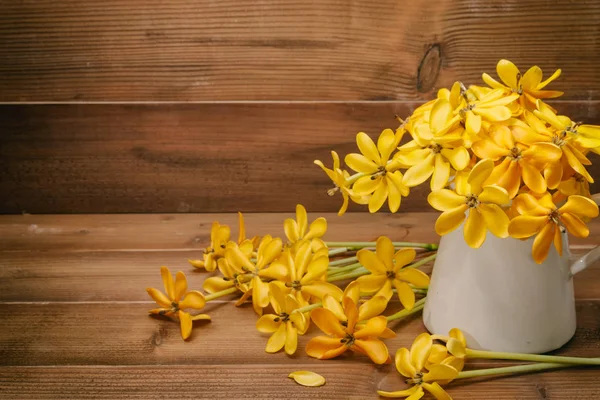 yellow gardenia flower in vase on wooden background with copy sp